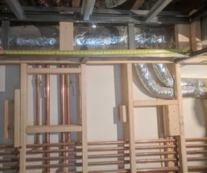 Basement renovation with pipes relocated behind wall framing