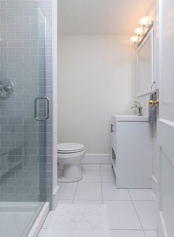Small Toilet Next to Gray Brick Shower
