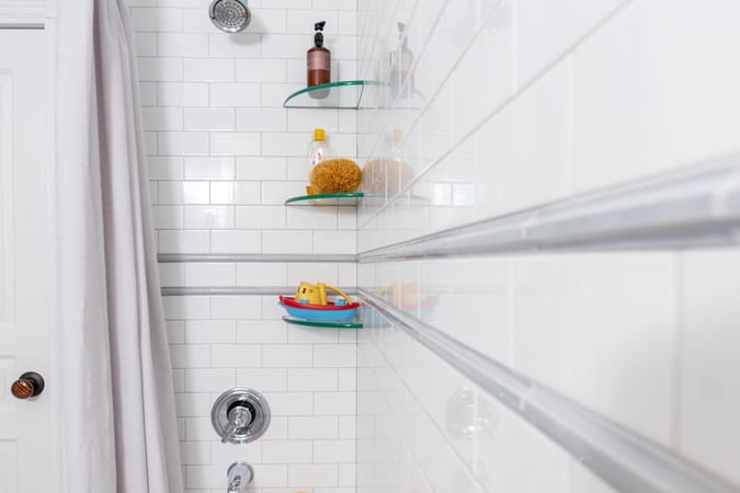 White Brick Shower Featuring Some Shampoo on Glass Shelves