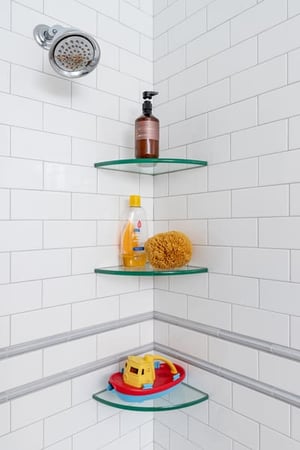 White Brick Shower Featuring Some Shampoo on Glass Shelves