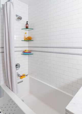 White Brick Shower Featuring Some Shampoo on Glass Shelves and a Large Tub