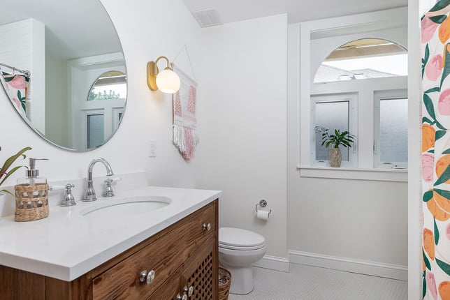 Colorful Bathroom Featuring White Walls and Surfaces with Splashes of Color on the Floor Mat and Shower Curtain
