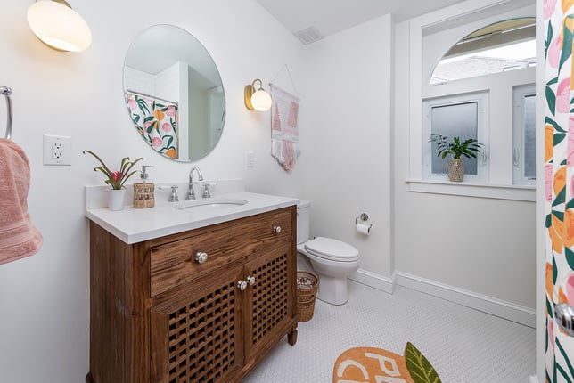 Colorful Bathroom Featuring White Walls and Surfaces with Splashes of Color on the Floor Mat and Shower Curtain