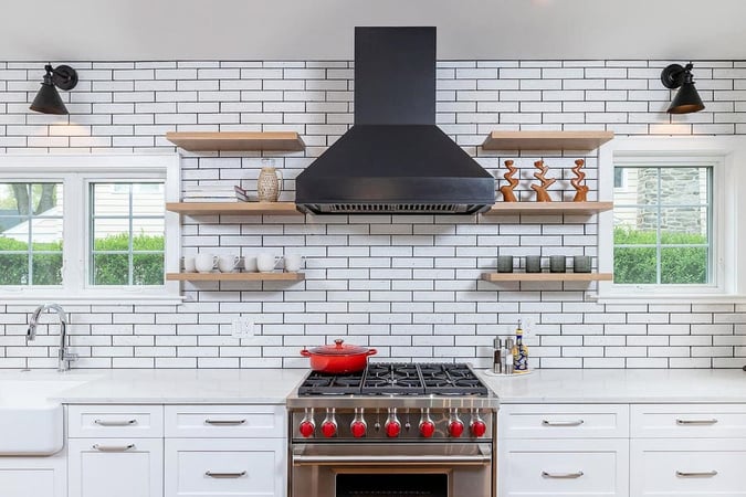 Farmhouse brick style kitchen remodel with metal stove with red knobs by Bellweather Design-Build in the Main Line