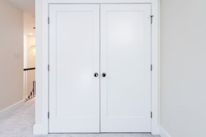 Closed white closet doors with hidden washer and dryer inside by Bellweather Design-Build in Philly