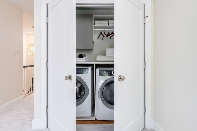 Hidden white washer and dryer in closet in hallway by Bellweather Design-Build in Philadelphia