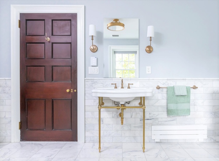 Bathroom sink with gold fixtures and wood door